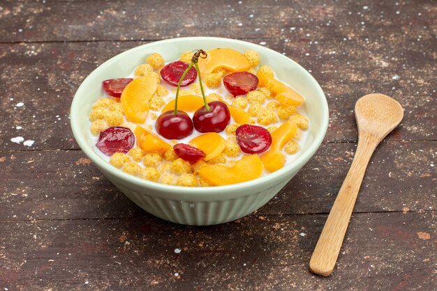 Vista frontal de cereales con leche dentro de la placa con frutas frescas sobre el fondo marrón de madera cereales cereales desayuno