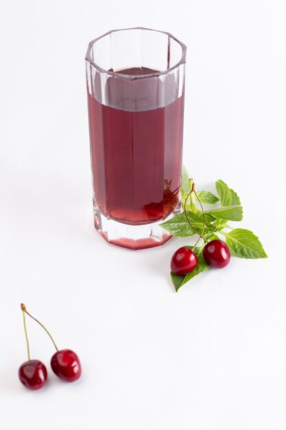 Vista frontal de cerezas frescas agrias y suaves junto con jugo de cereza en blanco