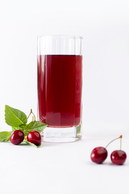 Vista frontal de cerezas frescas agrias y suaves junto con jugo de cereza en blanco