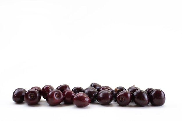 Una vista frontal de las cerezas rojas frescas suaves y jugosas en blanco, color de la fruta madura