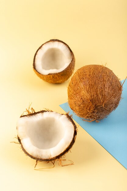 Una vista frontal cerrada cocos enteros y en rodajas lechoso dulce suave aislado en el fondo de color azul-crema-helado de frutas exóticas tropicales