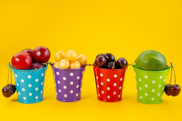 Una vista frontal de cestas con frutas coloridas frescas y suaves sobre amarillo, color de fruta verano suave