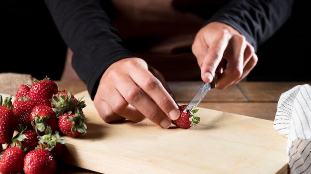 Vista frontal del chef en delantal cortando fresas