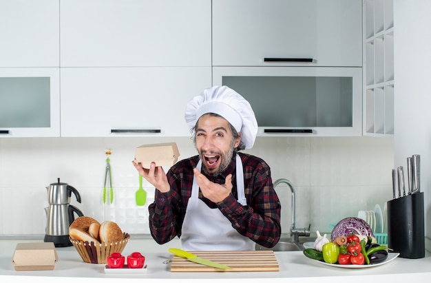 Vista frontal del chef masculino en delantal con caja en la cocina