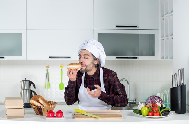 Vista frontal del chef masculino con los ojos cerrados oliendo pan en la cocina