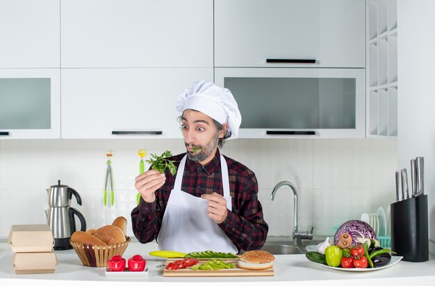 Vista frontal del chef masculino con verduras en la cocina