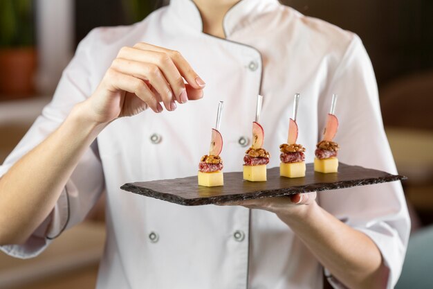 Vista frontal del chef sosteniendo un delicioso plato de comida