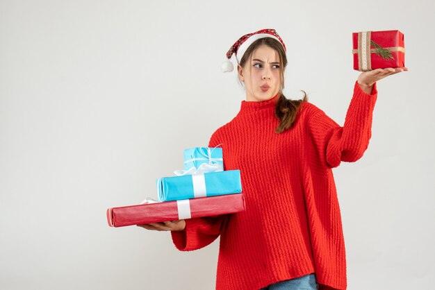 Vista frontal chica confundida con gorro de Papá Noel comparando su regalo de Navidad