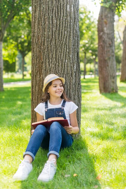 Vista frontal chica con libro mirando a otro lado