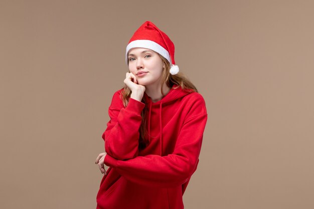 Vista frontal chica de navidad posando con capa roja sobre fondo marrón modelo vacaciones navidad