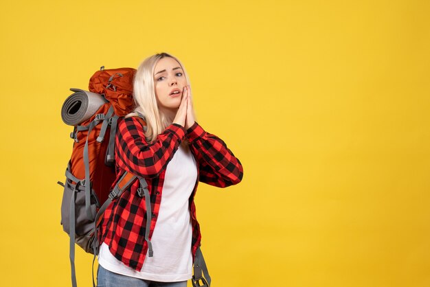 Vista frontal chica rubia con su mochila uniendo sus manos