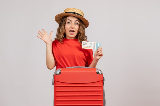 Vista frontal de la chica de vacaciones con valija con billete de viaje