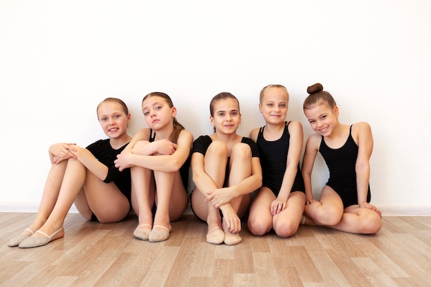 Vista frontal de chicas en leotardos posando durante una sesión de ballet