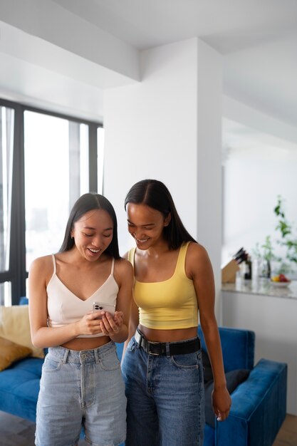 Vista frontal chicas sonrientes con teléfono inteligente