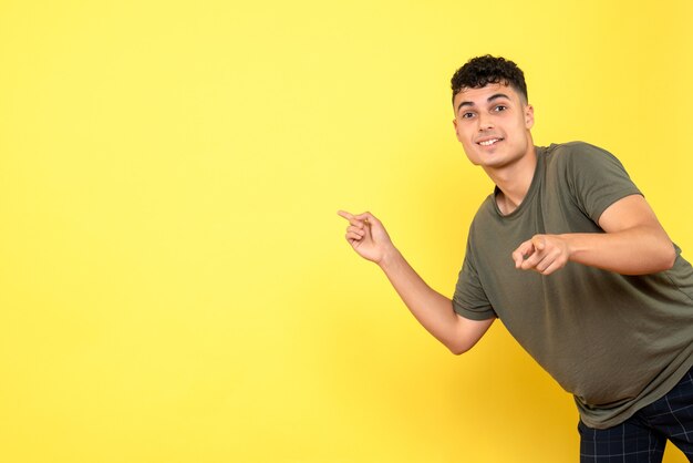 Vista frontal de un chico el chico bastante sonriente apunta a la pared