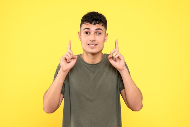 Vista frontal de un chico, el chico guapo sonriente apunta hacia arriba