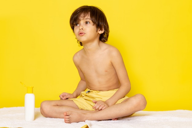 Foto gratuita vista frontal chico lindo adorable dulce en la toalla blanca y escritorio amarillo