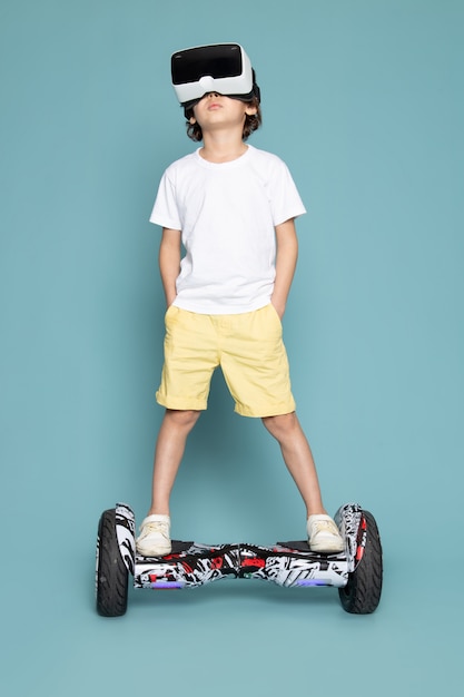 Foto gratuita una vista frontal chico lindo jugando vr en el segway en camiseta blanca en el piso azul