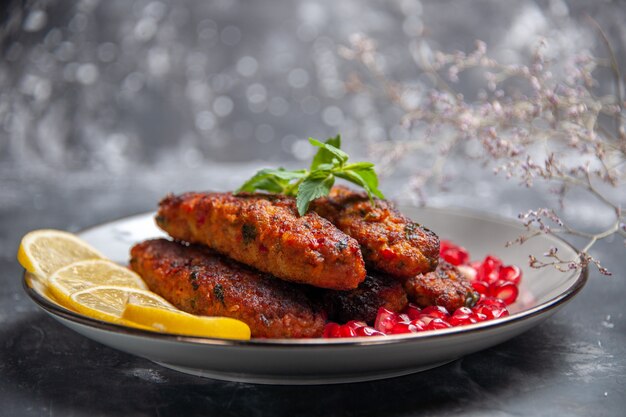 Vista frontal chuletas de carne largas con limón y granadas