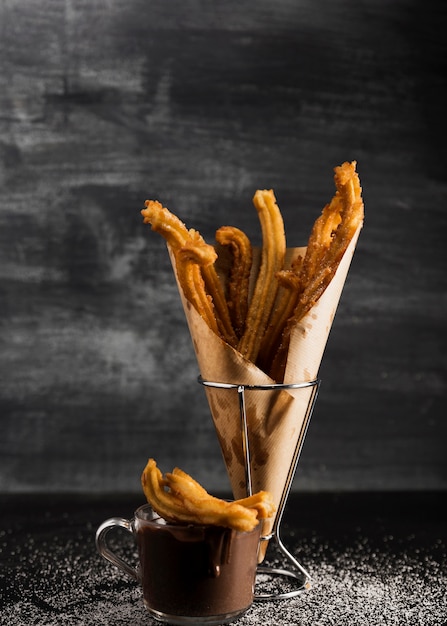 Vista frontal de churros en papel de envolver y chocolate