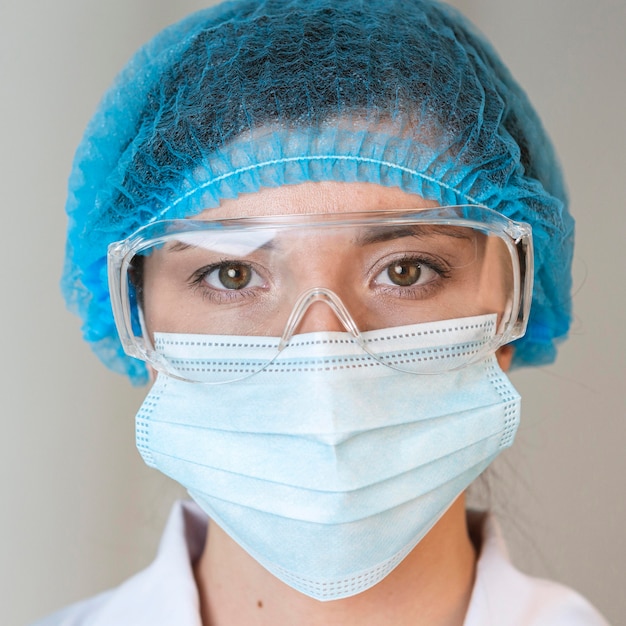 Vista frontal de la científica con gafas de seguridad, redecilla y mascarilla médica