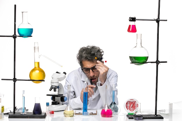 Vista frontal científico masculino sosteniendo muestras sobre fondo blanco laboratorio covid virus ciencia salud