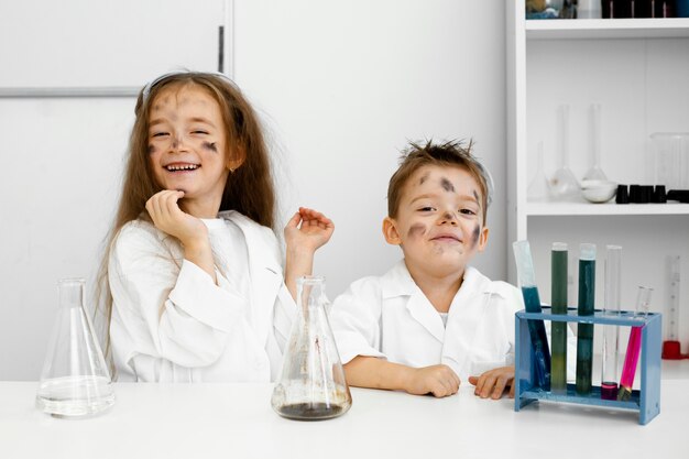 Vista frontal de científicos de niños y niñas en el laboratorio con tubos de ensayo y experimento fallido