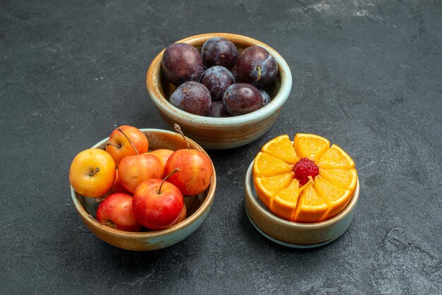 Vista frontal de ciruelas frescas con cerezas dulces sobre fondo oscuro fruta fresca suave