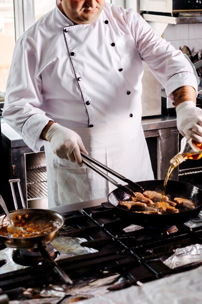 Vista frontal cocinar carne frita dentro de una sartén redonda en la cocina