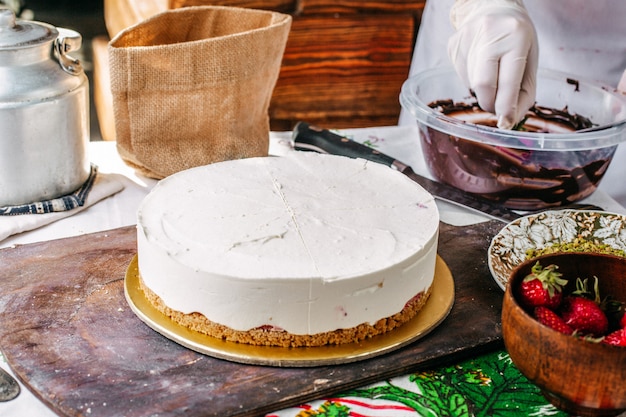 Una vista frontal cocinar haciendo pastel de choco y pastel de fresa en el proceso de hacer pastel redondo de crema deliciosa celebración de cumpleaños dulce