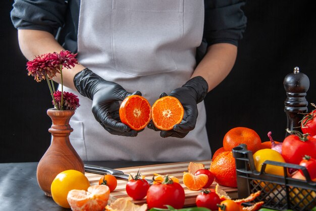 Vista frontal cocinera cortando mandarinas en ensalada de cocina oscura salud comida vegetal comida fruta trabajo dieta