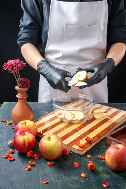 Vista frontal cocinera cortando manzanas en un plato de frutas oscuras dieta ensalada comida comida exótica jugo trabajo pastel pastel