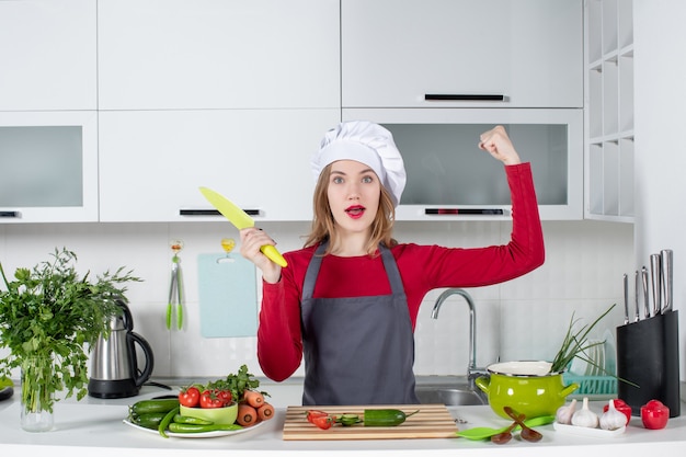 Vista frontal cocinera en delantal sosteniendo un cuchillo mostrando su fuerza