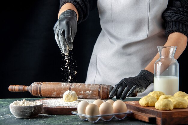 Vista frontal cocinera extendiendo la masa con harina en el trabajo oscuro cocina horno hotcake masa pastel pastel huevo trabajador