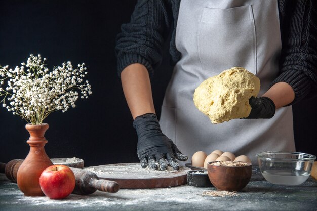 Vista frontal cocinera extendiendo la masa con harina en el trabajo oscuro masa cocina hotcake cocina panadería huevo