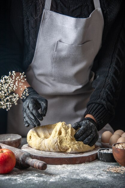 Vista frontal cocinera extendiendo la masa en huevo oscuro trabajo de cocina pastelería panadería masa de cocina hotcake