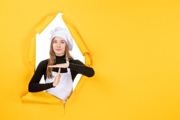 Vista frontal cocinera femenina en amarillo comida sol emoción cocina papel fotográfico color de cocina