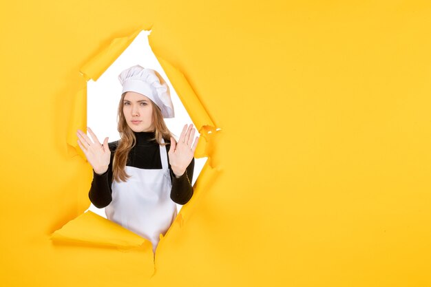 Vista frontal cocinera femenina en amarillo sol emoción cocina papel fotográfico trabajo de cocina color