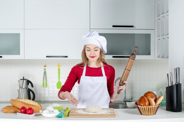 Vista frontal cocinera fuerte apuntando a la masa en la tabla de cortar en la cocina