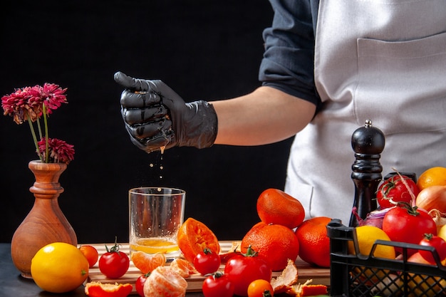 Vista frontal cocinera haciendo jugo de mandarina en una ensalada negra comida saludable trabajo de alimentos vegetales bebidas frescas dieta de frutas