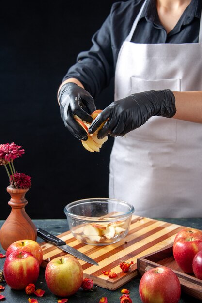 Foto gratuita vista frontal cocinera poniendo manzanas en un plato sobre jugo de fruta oscura ensalada de dieta comida comida trabajo exótico pasteles de tarta