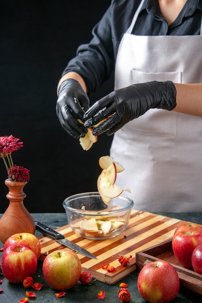 Vista frontal cocinera poniendo manzanas en un plato sobre jugo de fruta oscura tartas dietéticas ensalada de color comida comida pastel de trabajo exótico