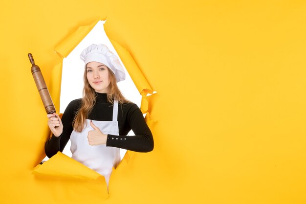 Vista frontal cocinera sosteniendo un rodillo en amarillo sol comida cocina trabajo cocina foto emoción