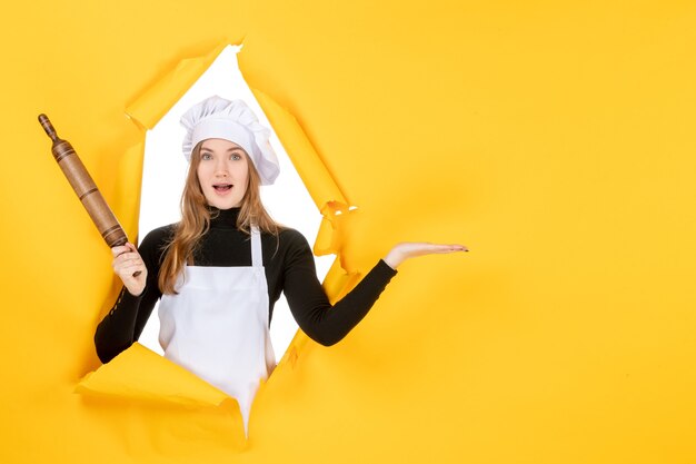 Vista frontal cocinera sosteniendo un rodillo en amarillo sol comida color cocina trabajo cocina