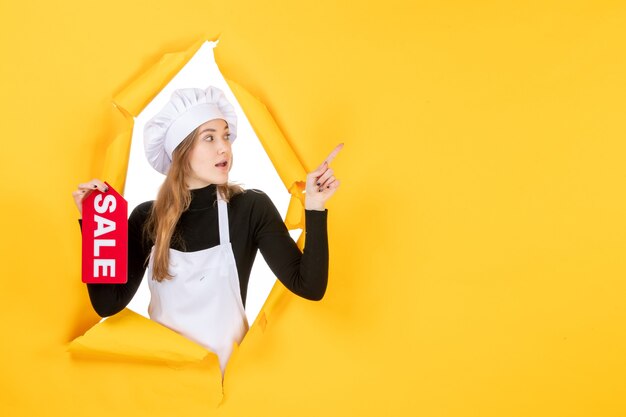 Vista frontal cocinera sosteniendo rojo venta escribiendo en color amarillo trabajo cocina cocina emoción comida foto