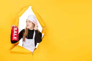 Foto gratuita vista frontal cocinera sosteniendo rojo venta escribiendo en color amarillo trabajo cocina emociones comida foto cocina