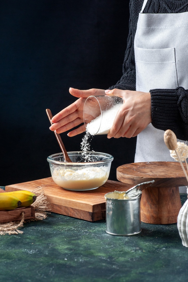 Foto gratuito vista frontal cocinera vertiendo coco en leche condensada sobre fondo oscuro