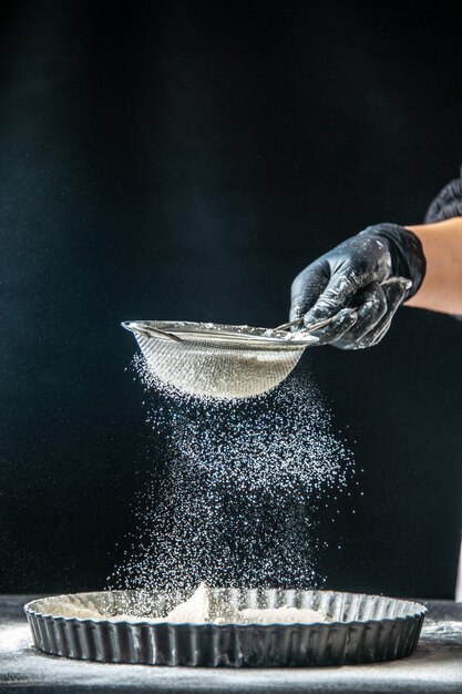 Vista frontal cocinera vertiendo harina blanca en la sartén en pasteles de huevo oscuro panadería hotcake pastelería cocina tartas de masa de cocina