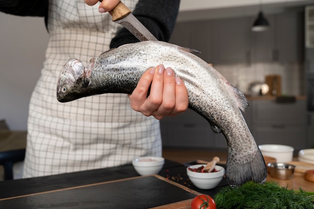 Vista frontal cocinero limpiando pescado en la cocina