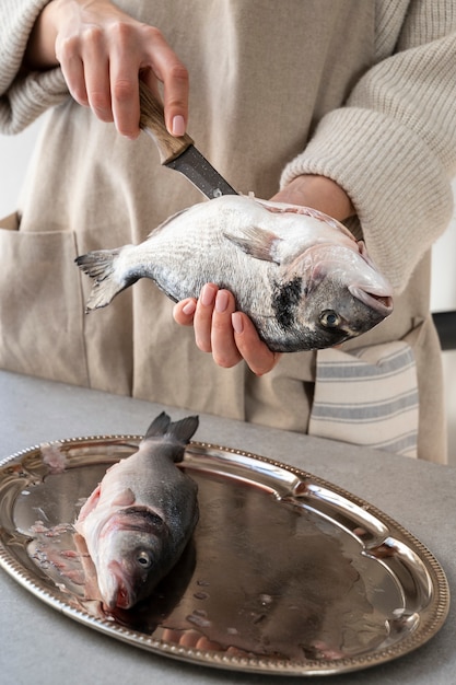 Foto gratuita vista frontal cocinero limpiando pescado en la cocina